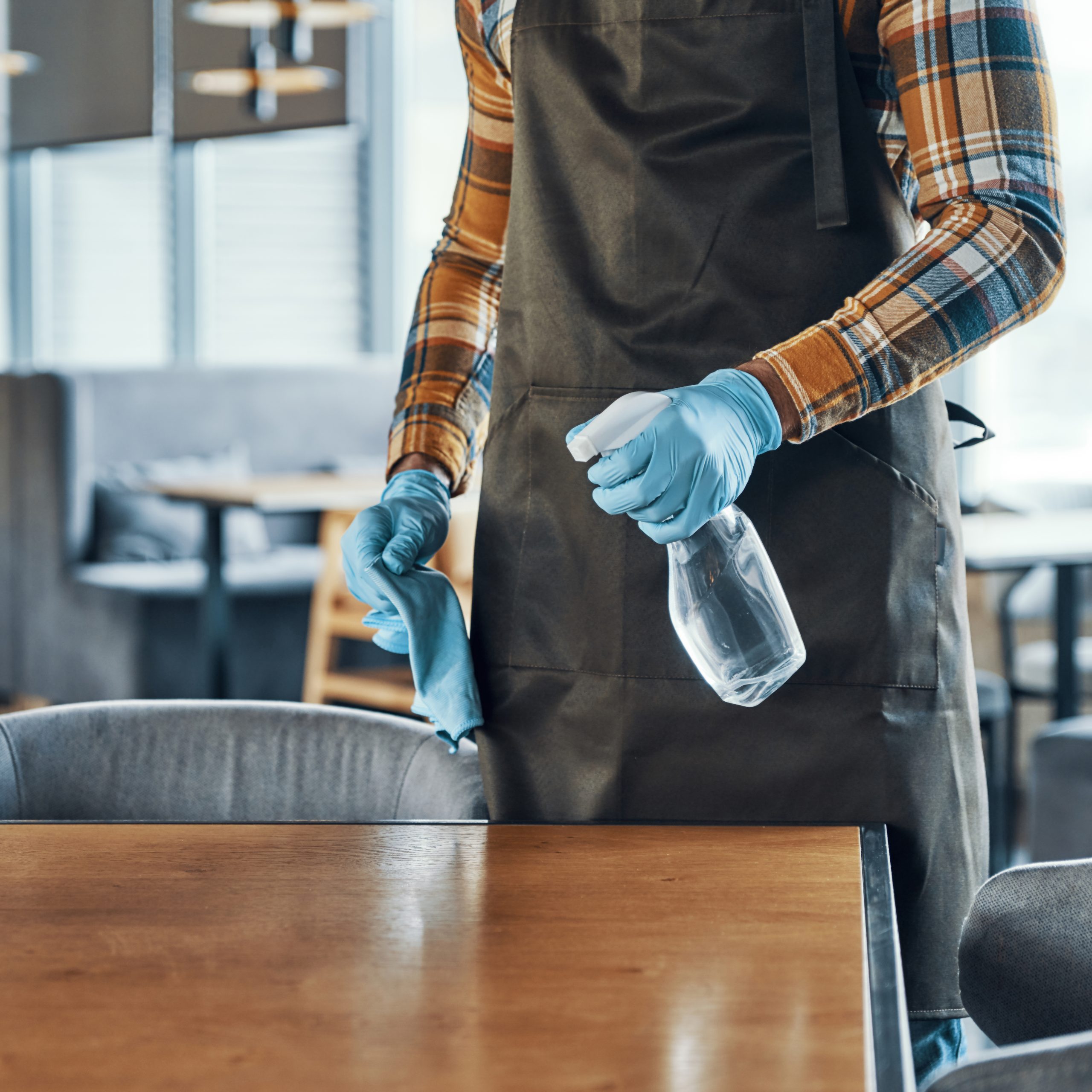 close up of man in protective gloves cleaning table for clients while preparing restaurant to open